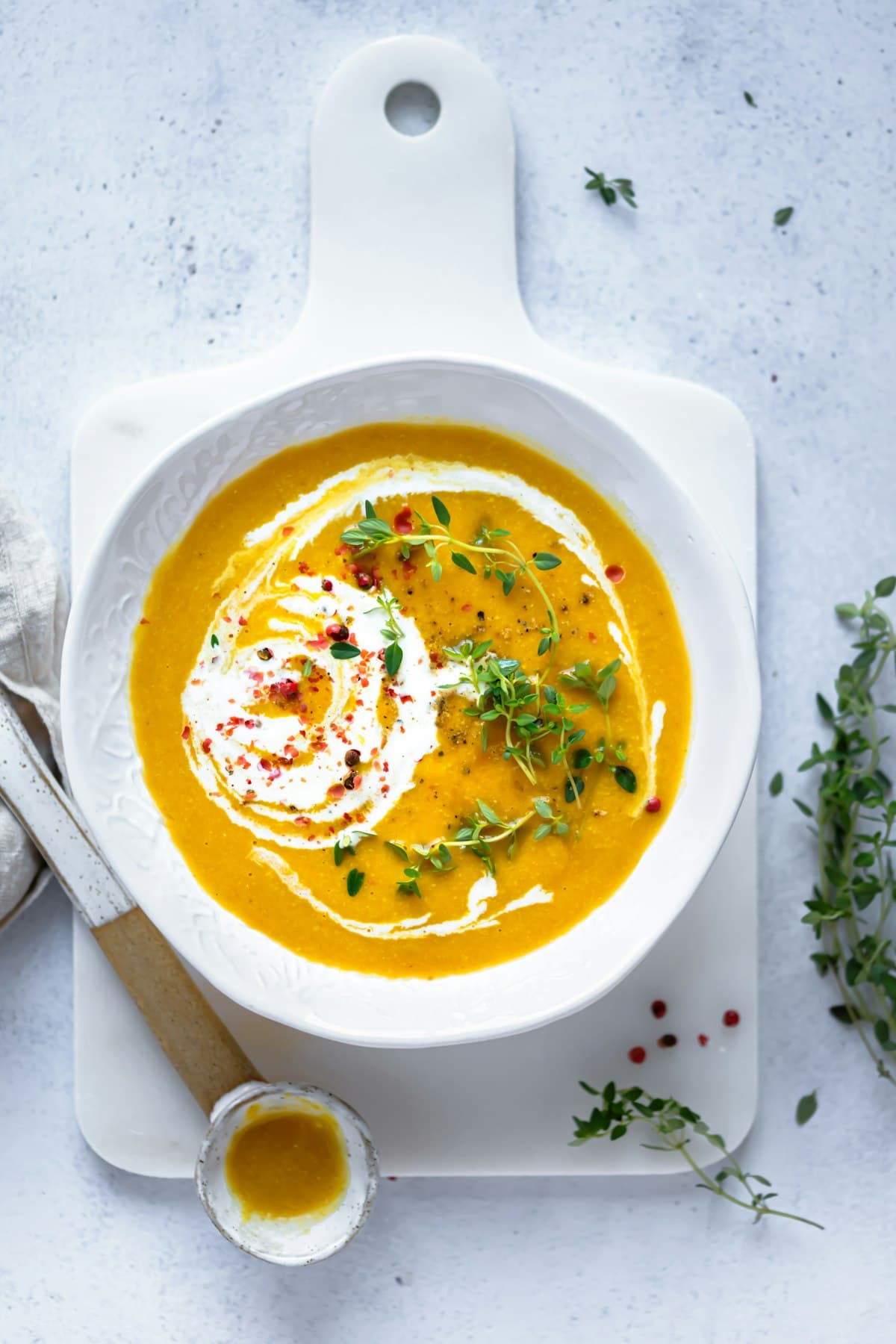 Tazón de caldo de huesos casero, humeante, con un hilo de crema y tomillo